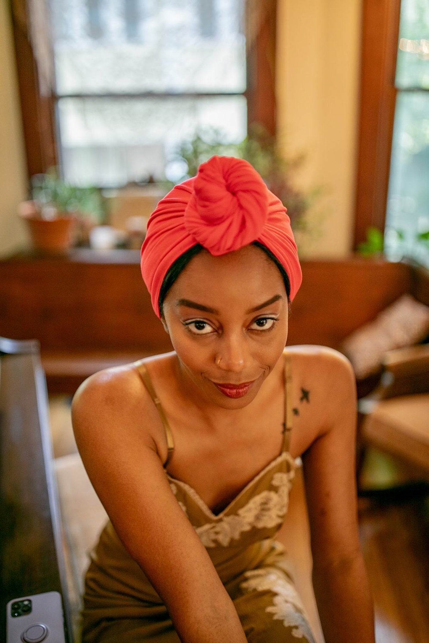 woman sits on a piano stool while drying her hair with a pink bamboo hair towel by capillum