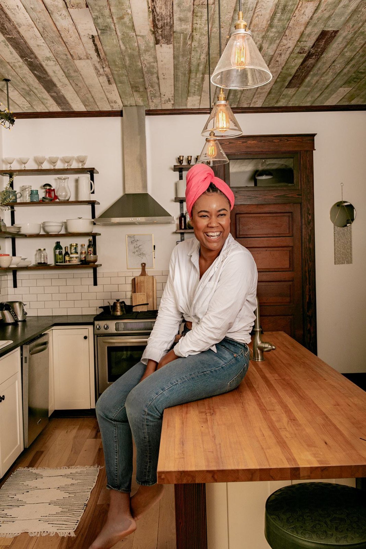 woman laughs while sitting on her kitchen island drying her hair with her Capillum Hair Towel in Pink 