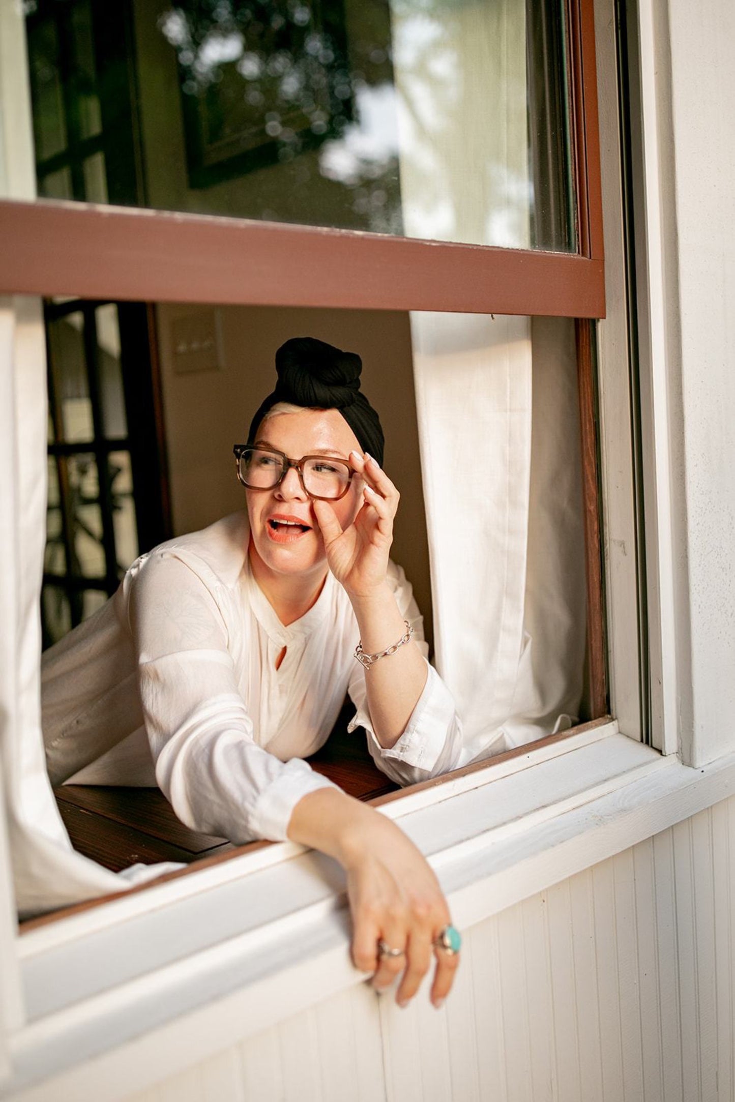 woman smiles from a window while she quickly dries her hair with the  luxury Bamboo hair towel by Capillum