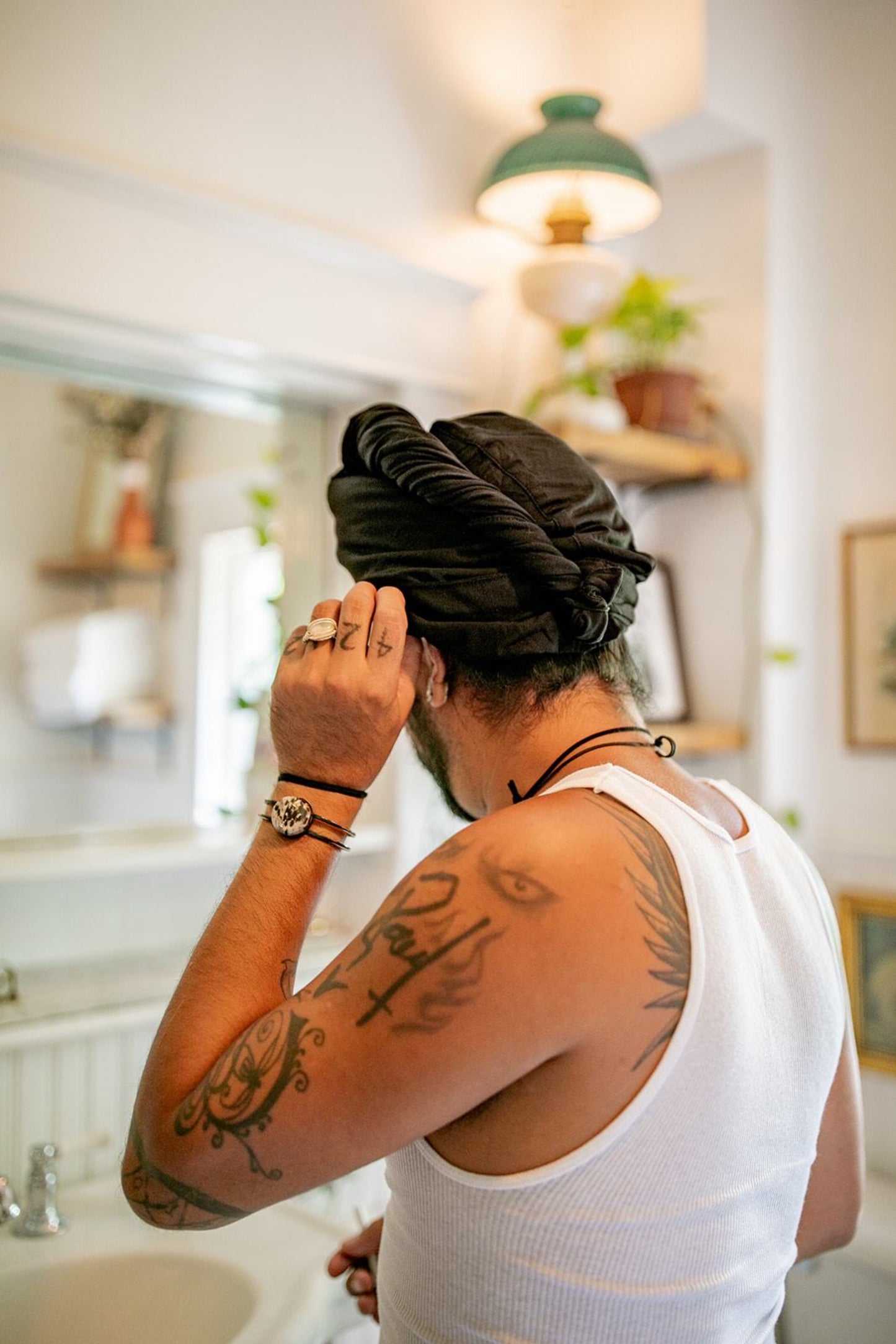 man gets ready in the bathrom while drying his hair with a Capillum Bamboo hair towel in black