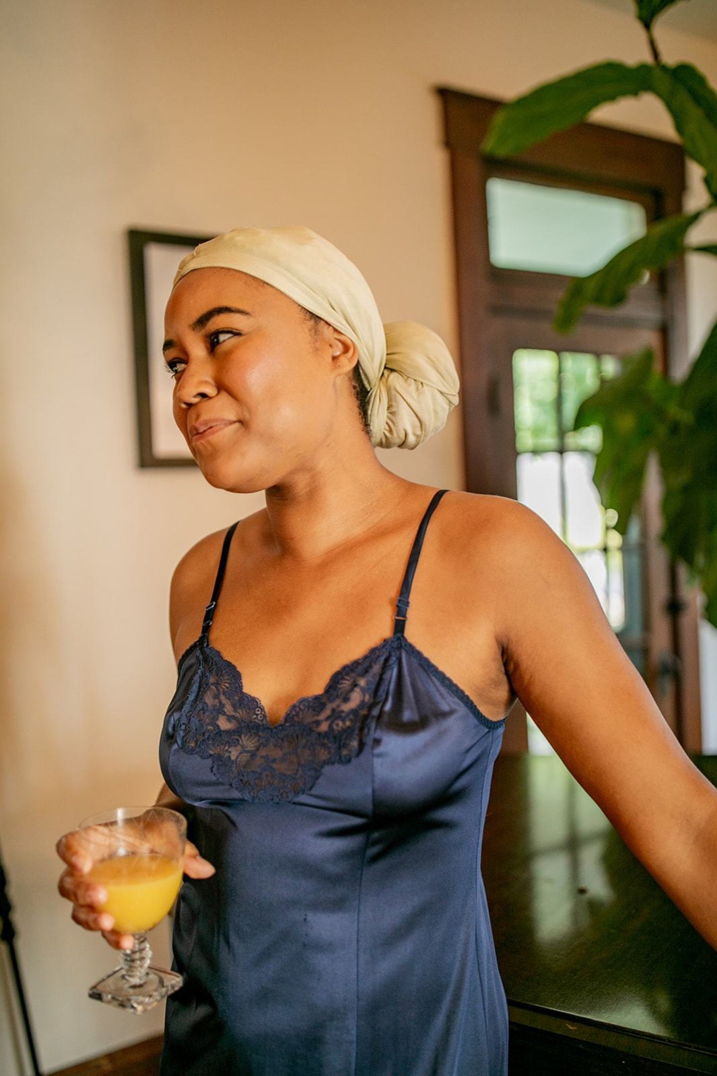 Woman drying her hair with a capillum bamboo hair towel in a light beige color.